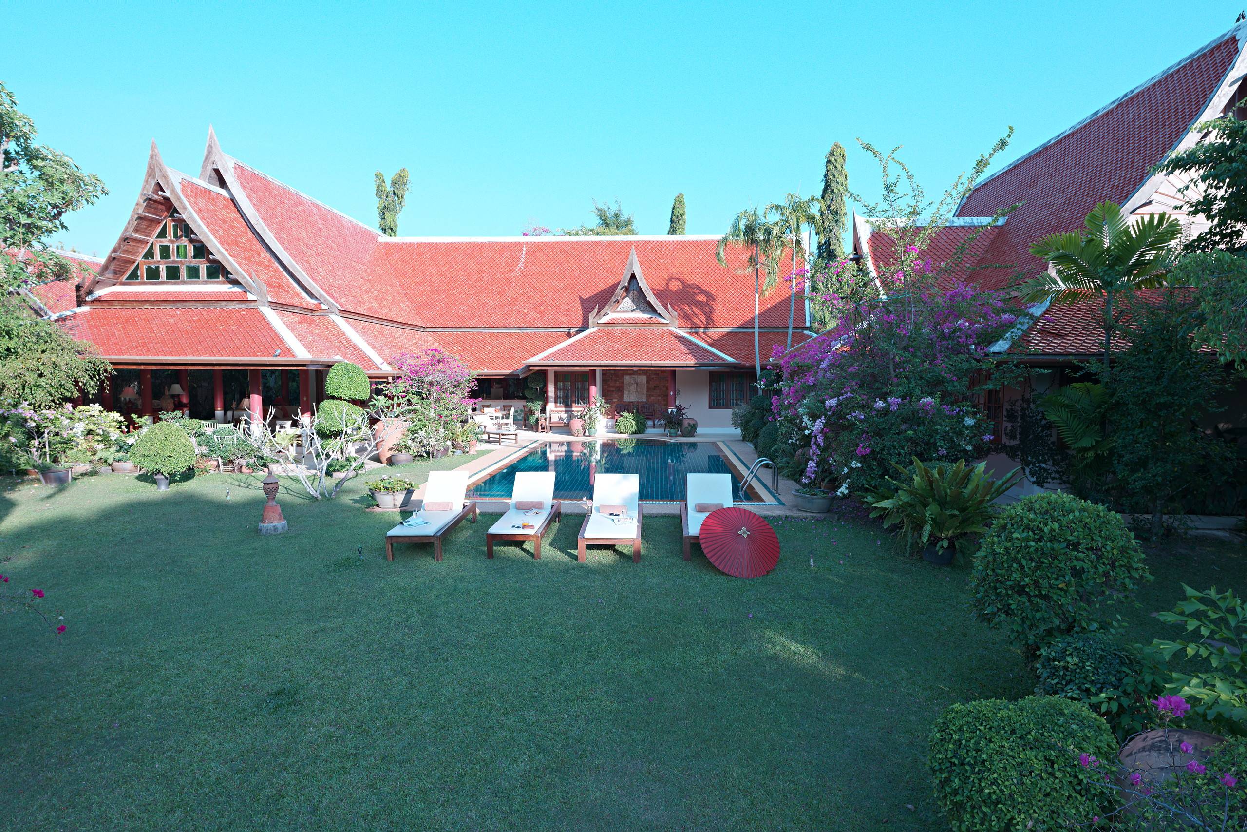 Die U-förmige Villa um ihren Pool, vom Garten aus gesehen