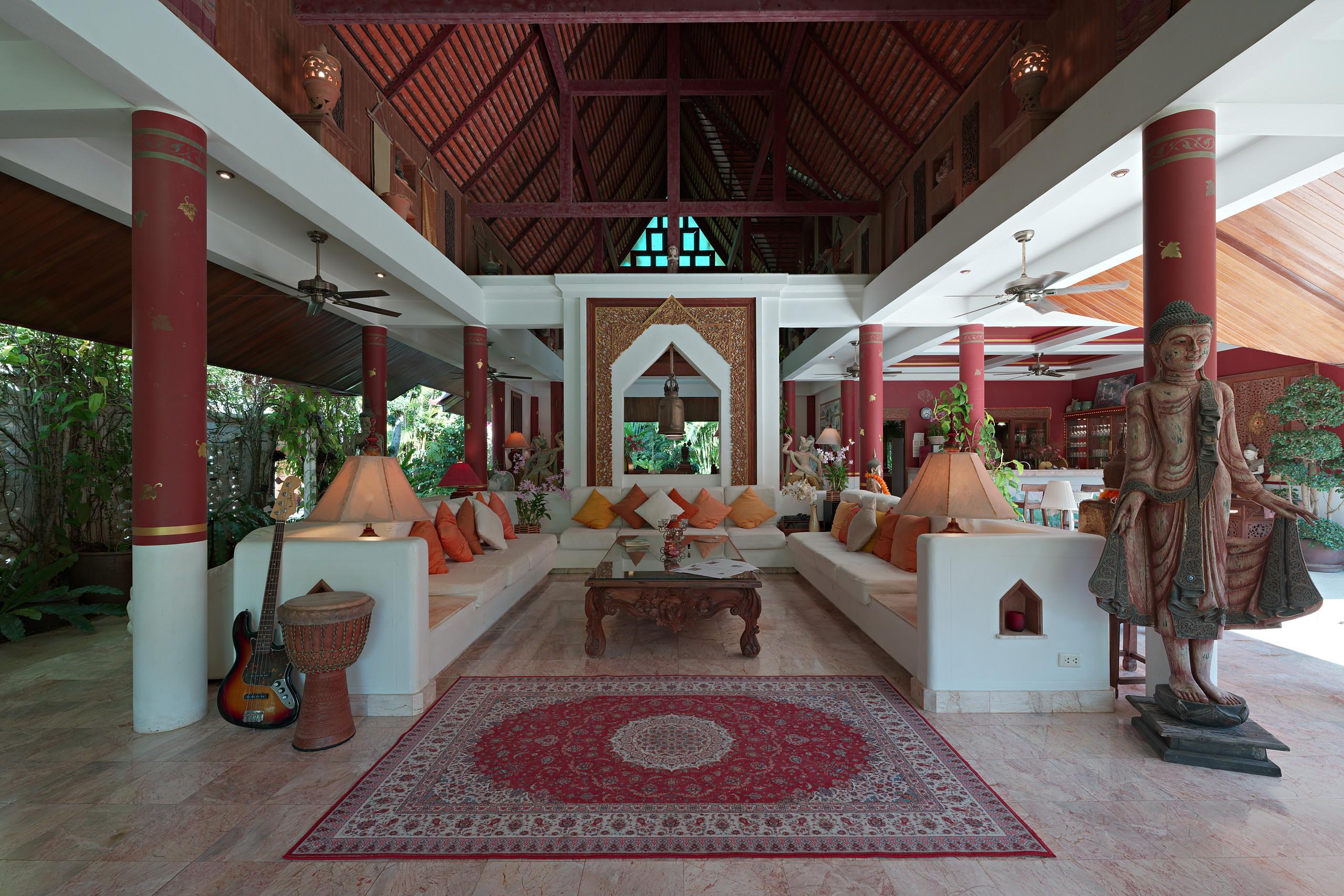 The open-air salon with teak Buddha statue, red columns and Persian carpet