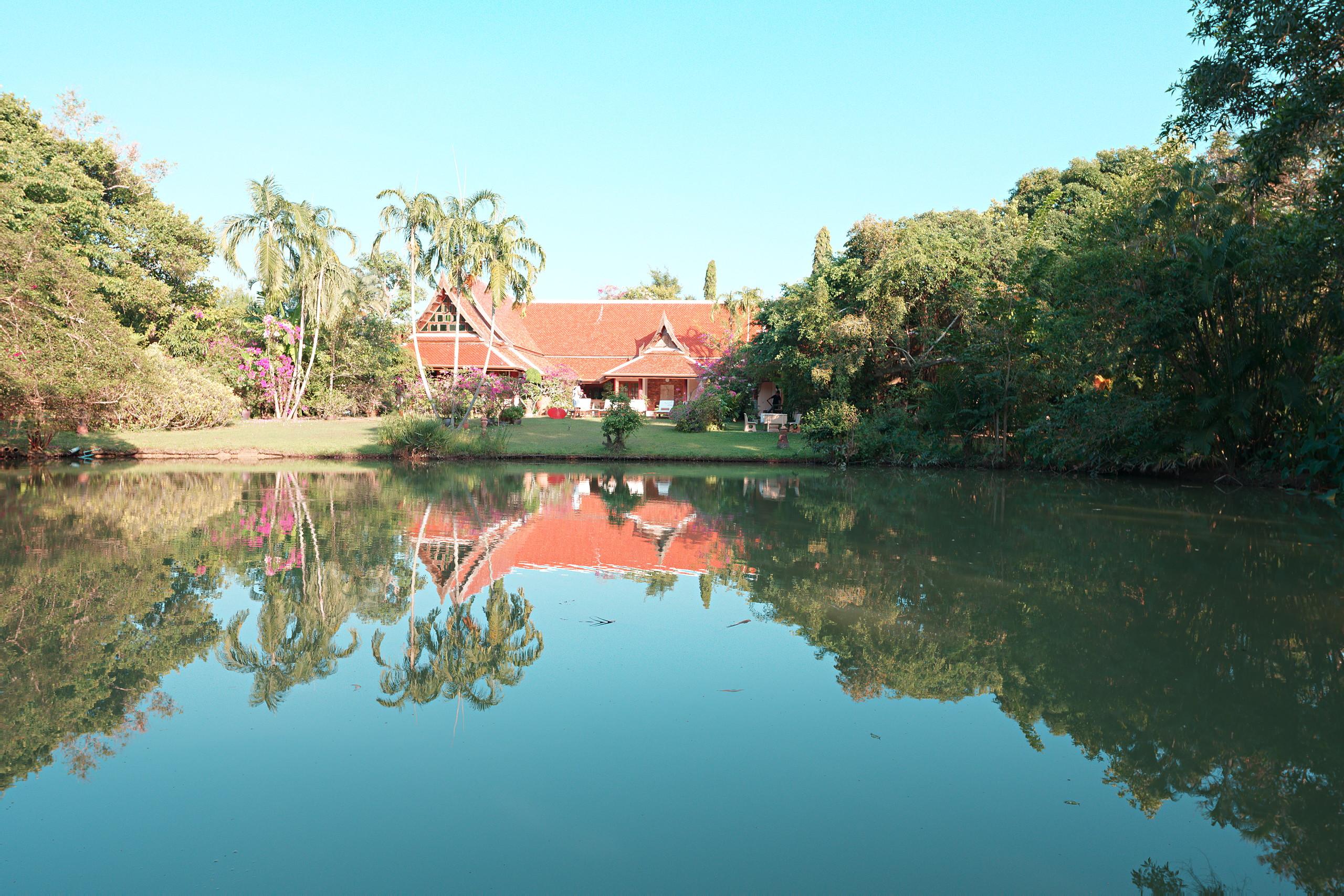 The pond at the heart of the park, reflecting palms and the villa roof