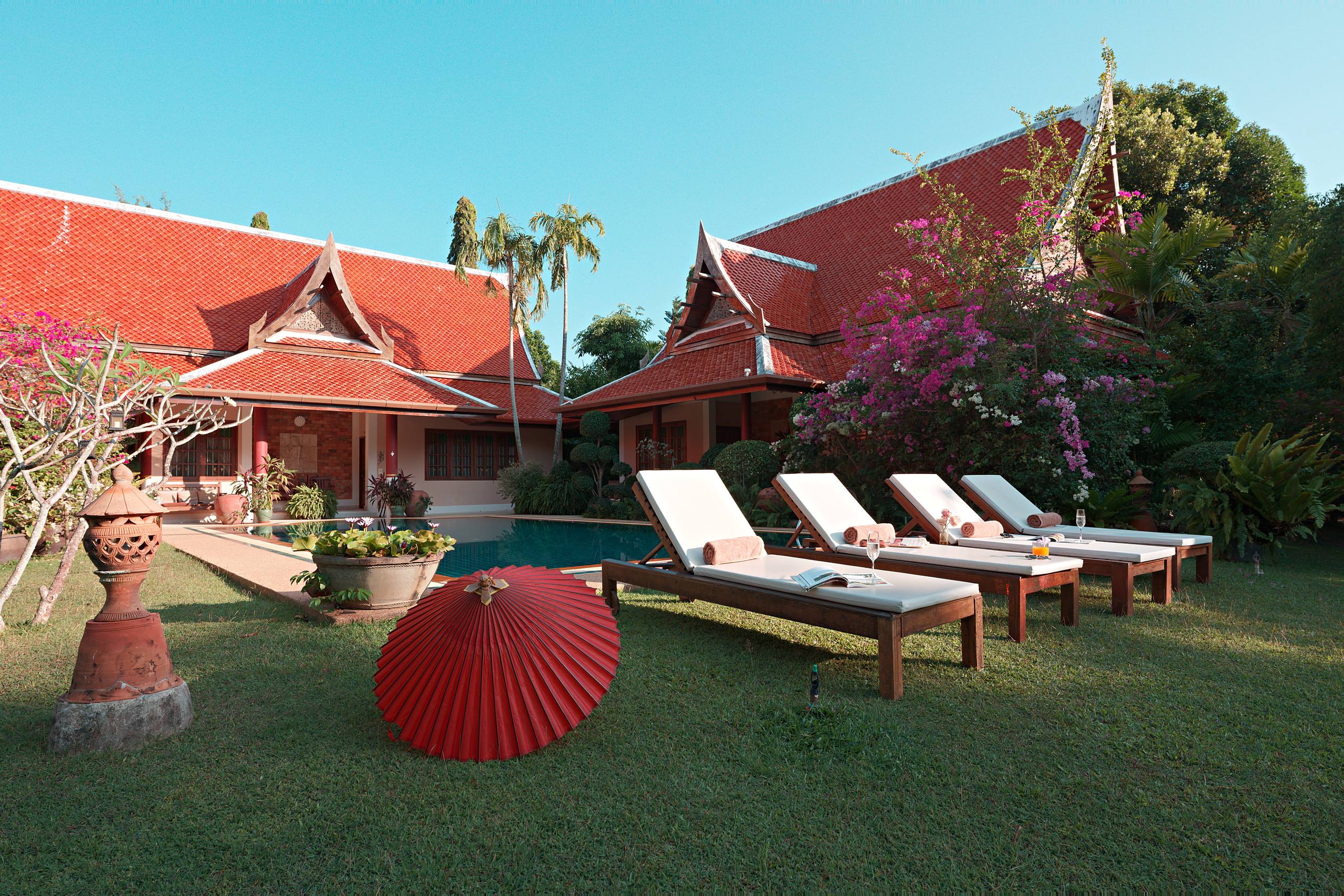 Sun loungers and red parasol on the lawn beside the pool