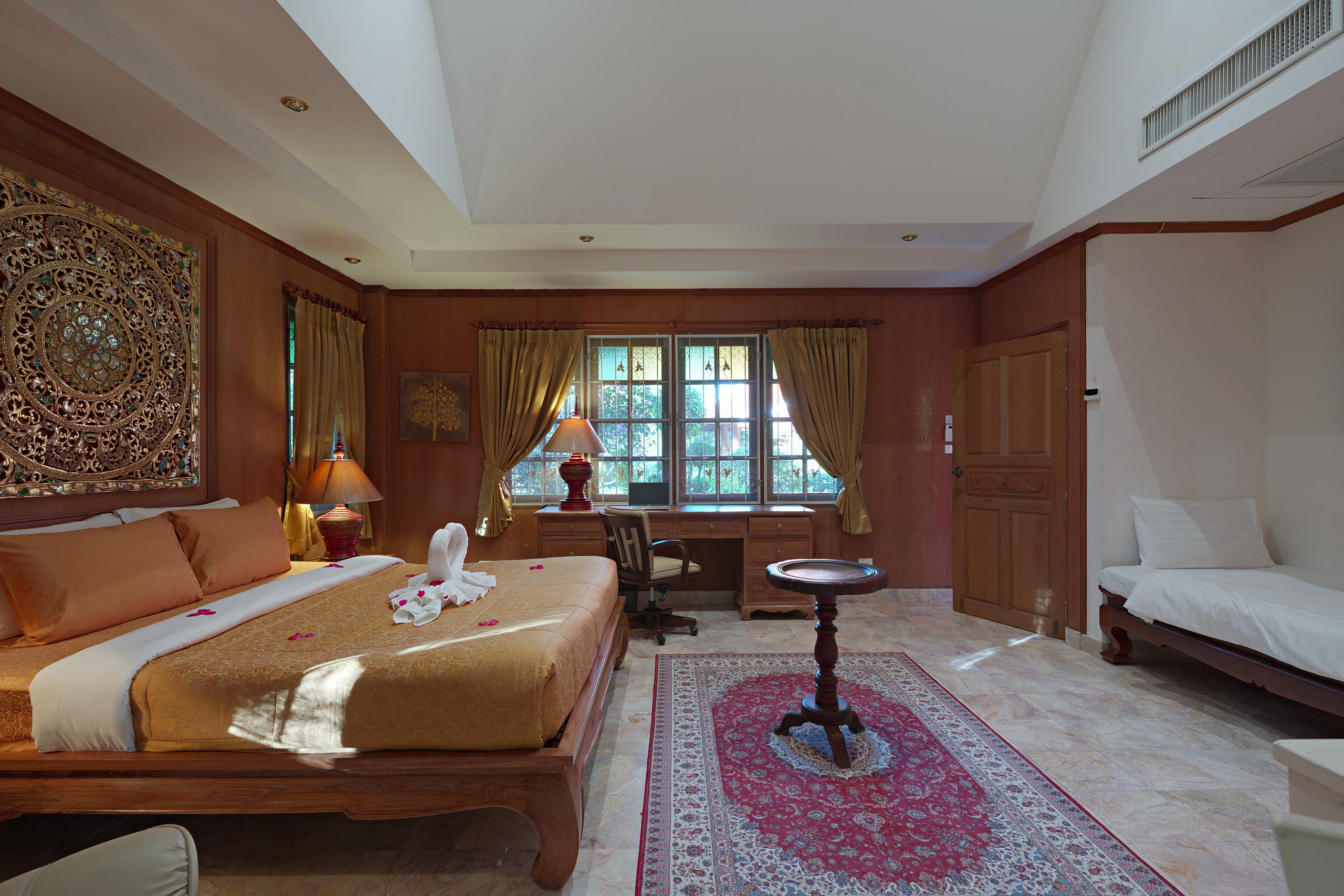 The master suite: king bed, carved teak panel and writing desk
